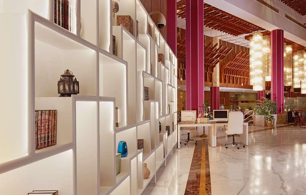 Makarem Ajyad Makkah Hotel Μέκκα Εσωτερικό φωτογραφία The photo shows a modern interior space, likely a lobby or lounge area of a stylish hotel or building. There is a partition wall made up of white shelving units illuminated from within, displaying various decorative items, books, and vases. The desig