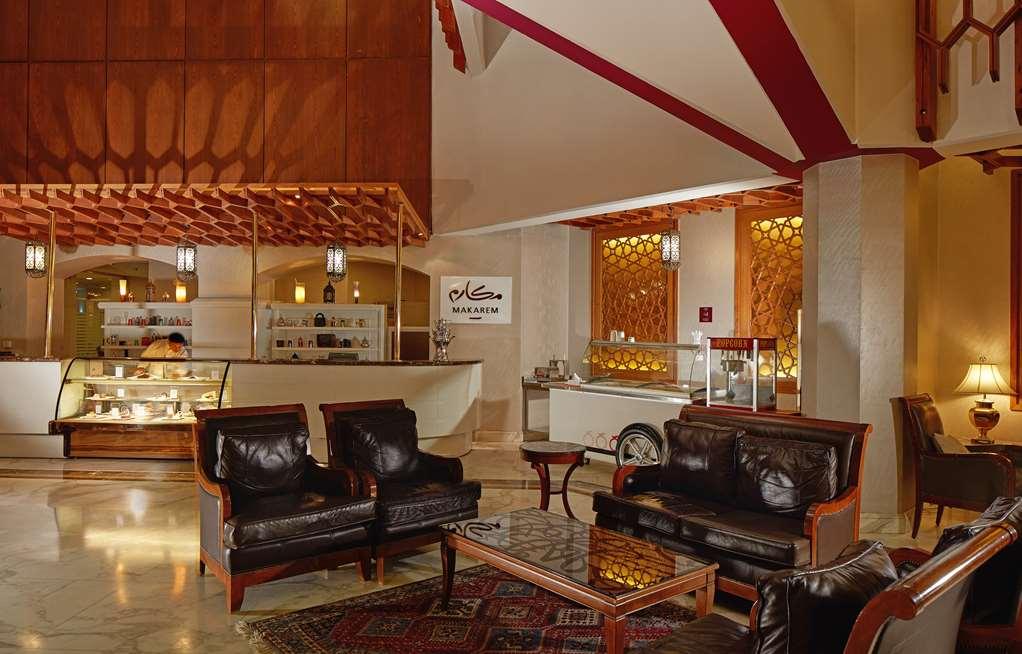 Makarem Ajyad Makkah Hotel Μέκκα Εσωτερικό φωτογραφία The photo shows a stylish interior of a lobby or lounge area. It features a seating arrangement with dark leather armchairs and a wooden table in front of them. The decor includes an intricate ceiling design and decorative wall elements that add a wa