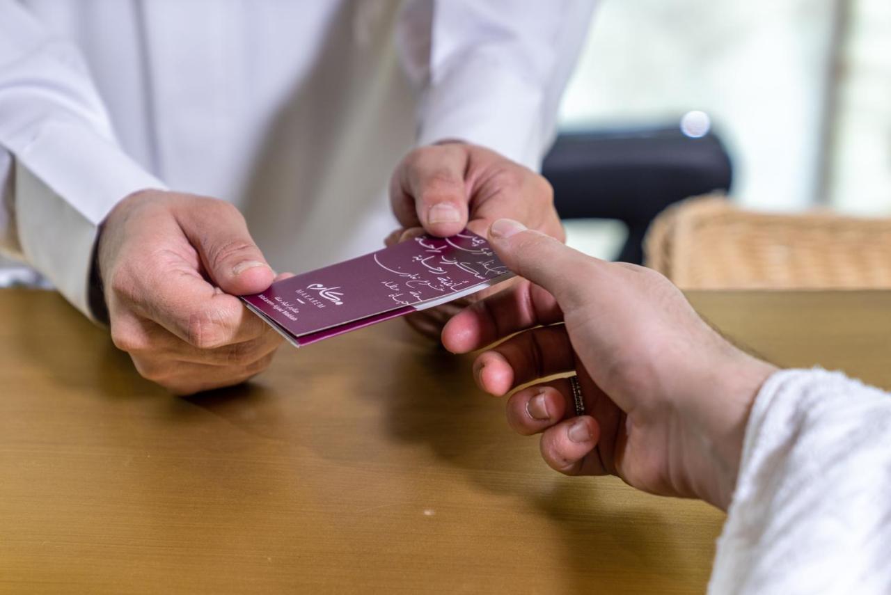 Makarem Ajyad Makkah Hotel Μέκκα Εξωτερικό φωτογραφία The photo shows two hands engaged in a transaction. One hand is extending a card towards another hand. The person handing over the card appears to be wearing a white garment, possibly a shirt or robe, while the person receiving the card has their han