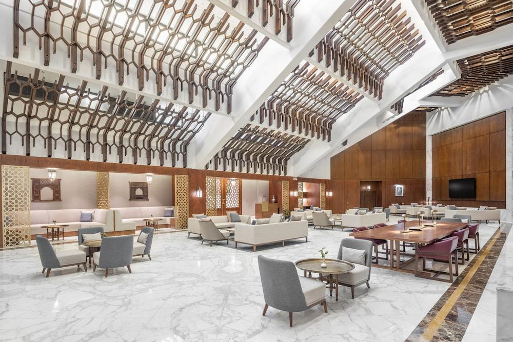 Makarem Ajyad Makkah Hotel Μέκκα Εξωτερικό φωτογραφία The photo shows a spacious and elegantly designed lobby area, likely within a hotel. The interior features high ceilings with a unique architectural design, showcasing wooden elements arranged in a geometric pattern. The flooring is a polished marble