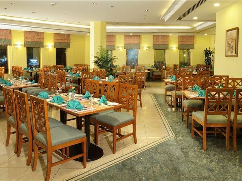Makarem Ajyad Makkah Hotel Μέκκα Εξωτερικό φωτογραφία The photo shows an interior view of a restaurant. It features wooden tables and chairs arranged neatly throughout the space. Each table is set with turquoise napkins, contributing to the overall decor. The walls are painted a soft yellow, and there a