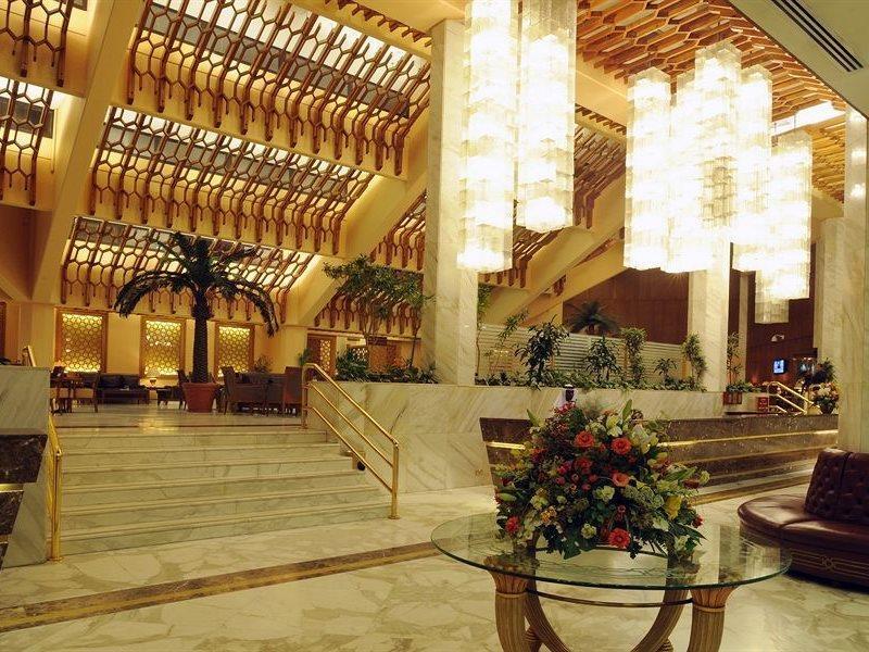 Makarem Ajyad Makkah Hotel Μέκκα Εξωτερικό φωτογραφία The photo shows a luxurious hotel lobby with elegant design features. It has high ceilings adorned with wooden beams and large, decorative light fixtures hanging from above. The lobby is brightly lit, creating a warm and inviting atmosphere. There ar