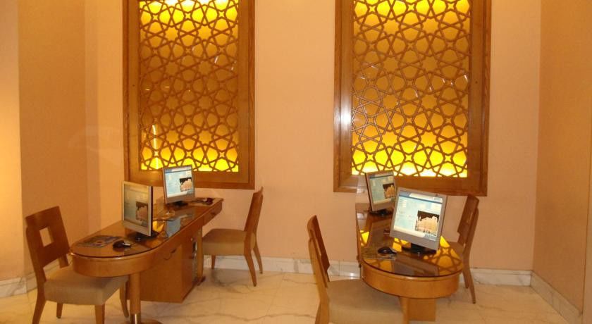 Makarem Ajyad Makkah Hotel Μέκκα Εξωτερικό φωτογραφία The image shows a room with a warm, inviting atmosphere, featuring two wooden desks equipped with computers. Each desk has a chair positioned in front of it. The walls are adorned with decorative panels that exhibit intricate patterns, illuminated by