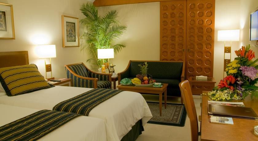 Makarem Ajyad Makkah Hotel Μέκκα Εξωτερικό φωτογραφία The photo shows a cozy hotel room that features two single beds with white linens and dark green and striped blankets. There is a decorative rug on the floor. Against one wall, there is a large wooden partition with a distinctive geometric pattern. T