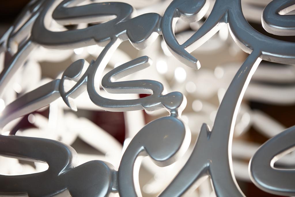 Makarem Ajyad Makkah Hotel Μέκκα Εξωτερικό φωτογραφία The photo shows a close-up of a white, artistic structure or piece of decor that features intricate, stylized lettering. The letters are intertwined and have a fluid, modern design. The focus on the details reveals the elegance of the curves and shap