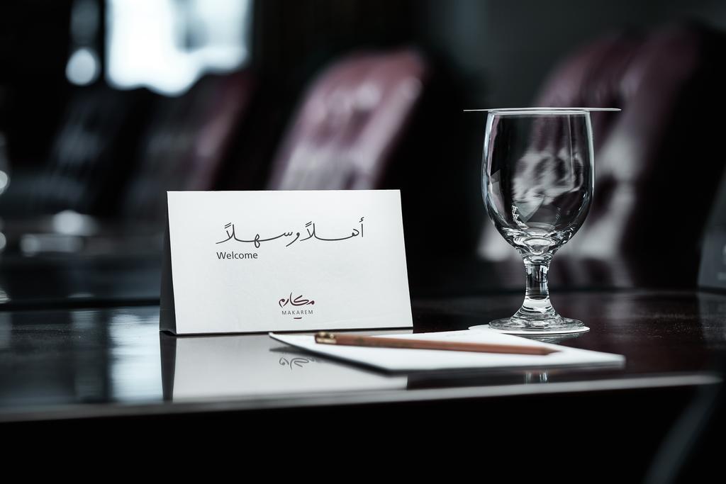 Makarem Ajyad Makkah Hotel Μέκκα Εξωτερικό φωτογραφία The photo depicts a well-arranged table setting. There is a card in both Arabic and English that says "Welcome," placed on the table. Next to the card, there is a clear glass and a pen resting on a piece of paper. The background features leather seat